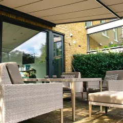 Mobiliario de exterior y plantas crean un espacio acogedor. Ideas para separar terrazas con estilo y privacidad.