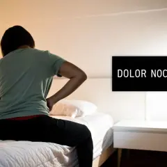 Persona con dolor de espalda sentada en la cama, buscando cómo dormir con hernia discal. El letrero dice "DOLOR NOCTURNO".