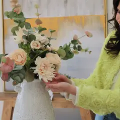 Mujer sonriente arregla un ramo de flores de tela, mostrando cómo limpiar flores de tela para mantener su belleza.