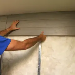Hombre instala paneles para insonorizar una habitación de forma casera. Aislamiento visible detrás.