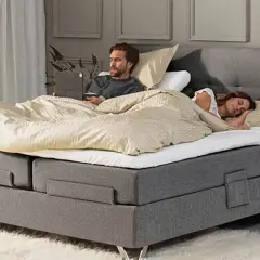 Hombre despierto en cama con portátil, mujer durmiendo a su lado. Un momento de paz para dormir juntos.