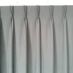 Cortina gris con pliegues de pinza, un ejemplo de los tipos de confección de cortinas que aportan elegancia y estructura.