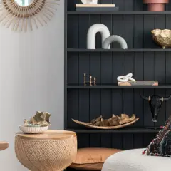 Estantería oscura con objetos decorativos en tonos tierra y dorados, mezclando muebles de distintos colores y texturas para un estilo ecléctico.