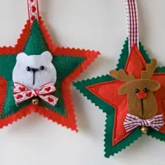 Adornos navideños de fieltro: un oso polar y un reno adornan estrellas rojas y verdes, listos para colgar.