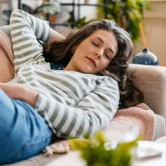 Mujer descansando en el sofá, con los ojos cerrados, lista para dormir antes de comer.