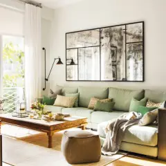 Un puf de terciopelo marrón es una opción acogedora que poner al lado del sofá, junto a una mesa de centro de madera y un sofá verde claro.