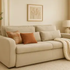 Sofá beige con cojines naranjas y manta tejida, perfecto para decorar sofá y crear un ambiente acogedor.