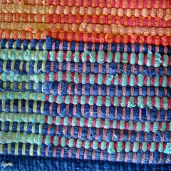 Textura de alfombra tejida a mano con hilos de colores: naranja, azul y verde. Ideal para aprender como hacer una alfombra.