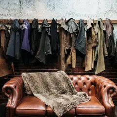 Abrigos de cuero colgados sobre un sofá Chesterfield. Si el cuero huele, aquí te explicamos como quitar el olor a cuero.