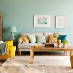Un salón moderno donde se combinan mostaza y azul en cojines, sillón y puerta.