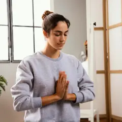 Mujer practicando mindfulness para combatir el insomnio, con las manos juntas en posición de rezo.