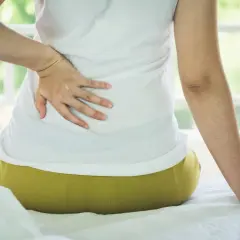 Persona con dolor de espalda, buscando cómo dormir con escoliosis.