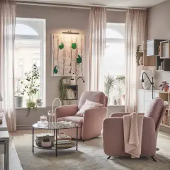 Acogedor salón rosa palo y gris con sillones cómodos, mesa de centro de cristal y estanterías llenas de libros y plantas.