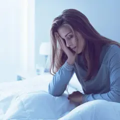 Mujer en la cama, con la mano en la frente, parece que me duermo y me despierto a cada rato.