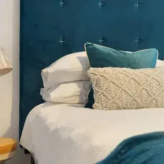 Cabecero de tela azul, almohadas y cama lista. Aprende como limpiar cabecero de tela para mantenerlo impecable.