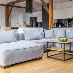 Sofá gris moderno con cojines, mesa de centro de madera y metal. Ideas para como hacer fundas de sofas faciles.