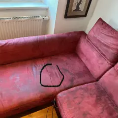 Un sofá de tela rojo con una mancha negra en forma de círculo. ¿Cómo reparar un sofá de tela roto?