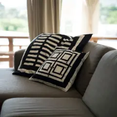 Sofá gris con cojines de diseño geométrico blanco y negro. Un detalle perfecto para combinar sofá negro y crear un ambiente moderno.