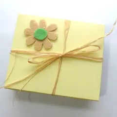Caja amarilla decorada con flor de fieltro y lazo de rafia. Ideas de manualidades con fieltro para el hogar.