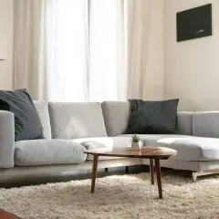 Sofá chaise longue gris con cojines oscuros, ideal para aprender como colocar cojines en chaise longue y crear un rincón acogedor.