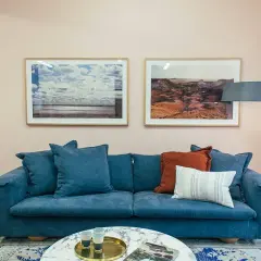 Sofá azul profundo con cojines que combinan a la perfección, creando un rincón acogedor.