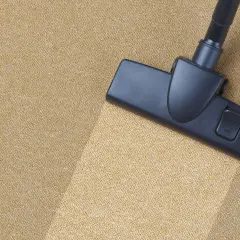 Cabezal de aspiradora limpiando una alfombra beige. Aprende como limpiar la alfombra en casa para un hogar impecable.