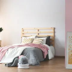 Dormitorio acogedor donde el beige y rosa combinan a la perfección en mantas y cojines. Una planta aporta frescura.
