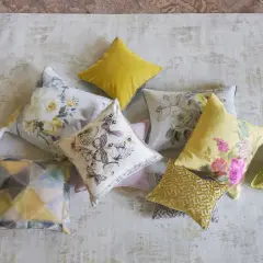 Varios cojines decorativos, algunos con estampados florales y mariposas, otros con diseños geométricos, todos son cuadros hechos con retazos de tela.