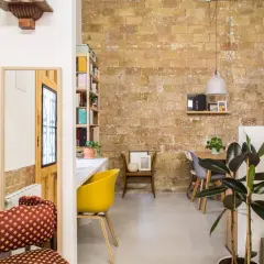Acogedor loft de 40 metros cuadrados con pared de ladrillo visto, comedor, zona de trabajo y plantas.