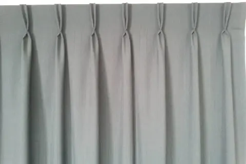 Cortina gris con pliegues de pinza, un ejemplo de los tipos de confección de cortinas que aportan elegancia y estructura.