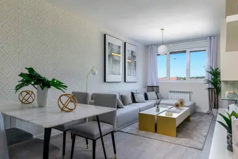 Salón rectangular dos ambientes con mesa de mármol, sofá modular gris y mesas doradas.