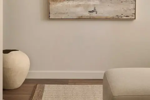 Ideas para decorar un pasillo: un jarrón grande y una alfombra geométrica bajo un cuadro abstracto.