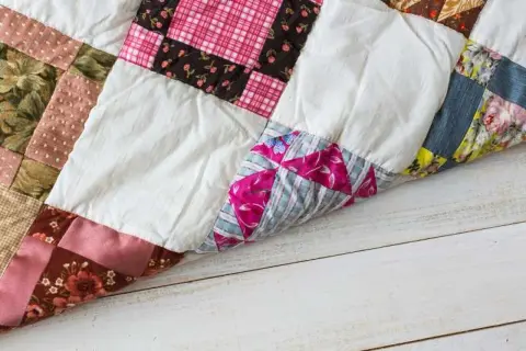 Colchas patchwork fáciles de hacer, con retazos de tela de flores, cuadros y rayas, sobre una mesa de madera.