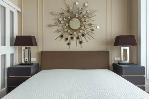 Un espejo sol y lámparas oscuras iluminan la habitación, demostrando como alegrar una habitación con muebles oscuros.