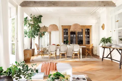 Elegante comedor con suelo de roble en espiga. Muebles de madera clara y mimbre combinan a la perfección, creando un ambiente cálido y acogedor.