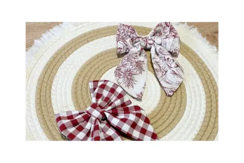 Dos lazos de tela, uno a cuadros rojos y blancos, otro con estampado floral en tonos burdeos, descansan sobre un tapete circular de cuerda.