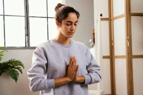 Mujer practicando mindfulness para combatir el insomnio, con las manos juntas en posición de rezo.