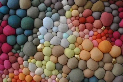 Textura orgánica de burbujas de **fibras sintéticas** en degradado de colores, con toques dorados.
