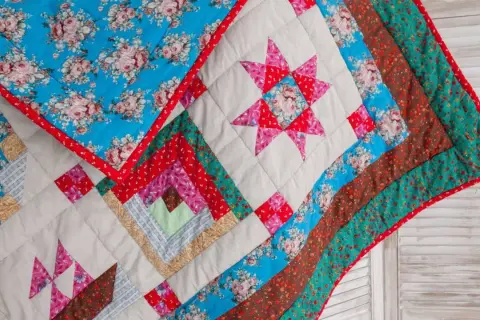 Manta de retazos con estrellas y bloques de troncos. Diseños florales y colores vibrantes, perfectos para cosas de patchwork fáciles.