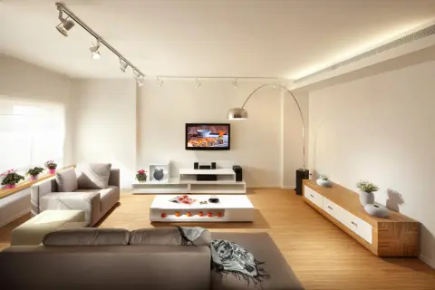 Iluminación moderna: cómo distribuir focos en el techo para crear ambiente en un salón con sofás, TV y mesa de centro.