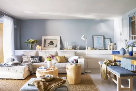 Sofá beige y cojines azules crean un ambiente acogedor. Tonos tierra y marinos se combinan en esta sala.