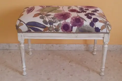 Descalzadora con tapizado floral en tonos morados y verdes, base blanca desgastada.