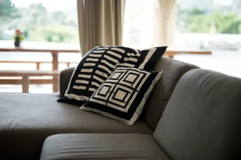 Sofá gris con cojines de diseño geométrico blanco y negro. Un detalle perfecto para combinar sofá negro y crear un ambiente moderno.