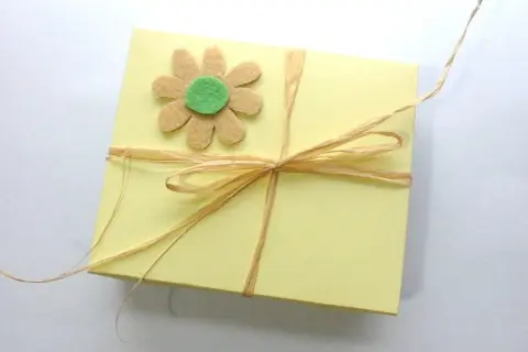 Caja amarilla decorada con flor de fieltro y lazo de rafia. Ideas de manualidades con fieltro para el hogar.