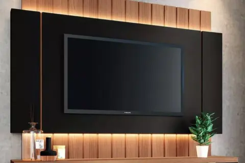Elegante decoración pared TV salón con panel negro, listones de madera y luz cálida. Un toque moderno y acogedor.