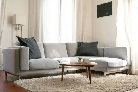 Sofá chaise longue gris con cojines oscuros, ideal para aprender como colocar cojines en chaise longue y crear un rincón acogedor.