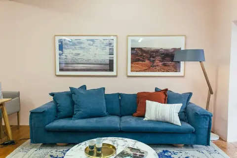 Sofá azul profundo con cojines que combinan a la perfección, creando un rincón acogedor.