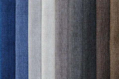 Muestrario de diferentes tipos de tela en tonos azules, grises y marrones, con texturas visibles.