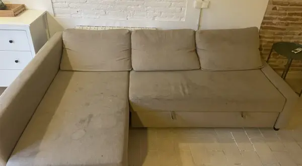 Sofá seccional beige con manchas, ideal para aprender como quitar manchas de chocolate del sofá.