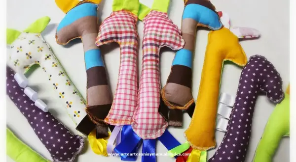 Manualidades de costura para el hogar: jirafas de tela de colores, algunas con cintas y estampados, perfectas para decorar o regalar.